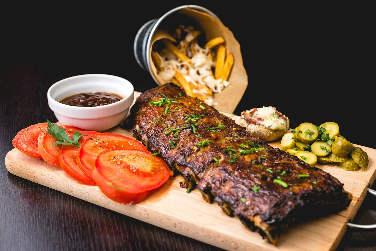 Costillar glaseado con barbacoa, patatas y tomate en tabla de madera
